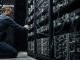 Engineer adjusting Bitcoin mining servers in a data center amid network power struggle over anti-spam proposal and disputed node support